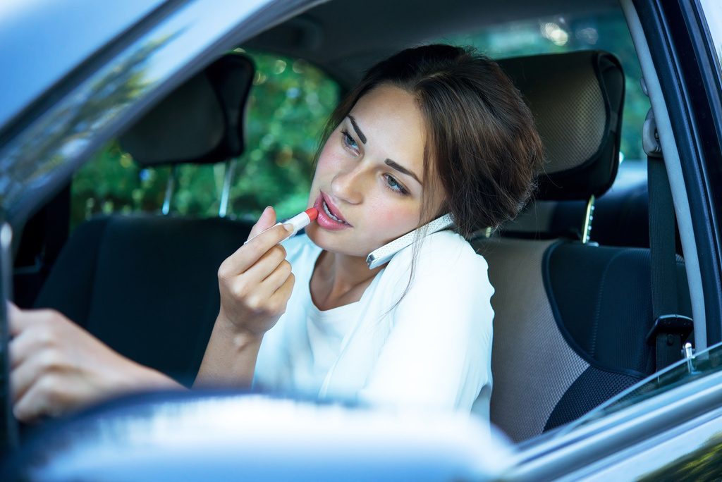 Driving Girl Putting on Lipstick while on the phone
